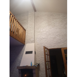 Płytki ceglane w kolorze łagodny grafit, ułożone w salonie z kominkiem. Styl loft od Petraart.