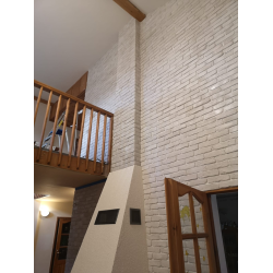 Cegła dekoracyjna ułożona na dużej powierzchni w salonie z kominkiem. kolor łagodny grafit od Petraart.